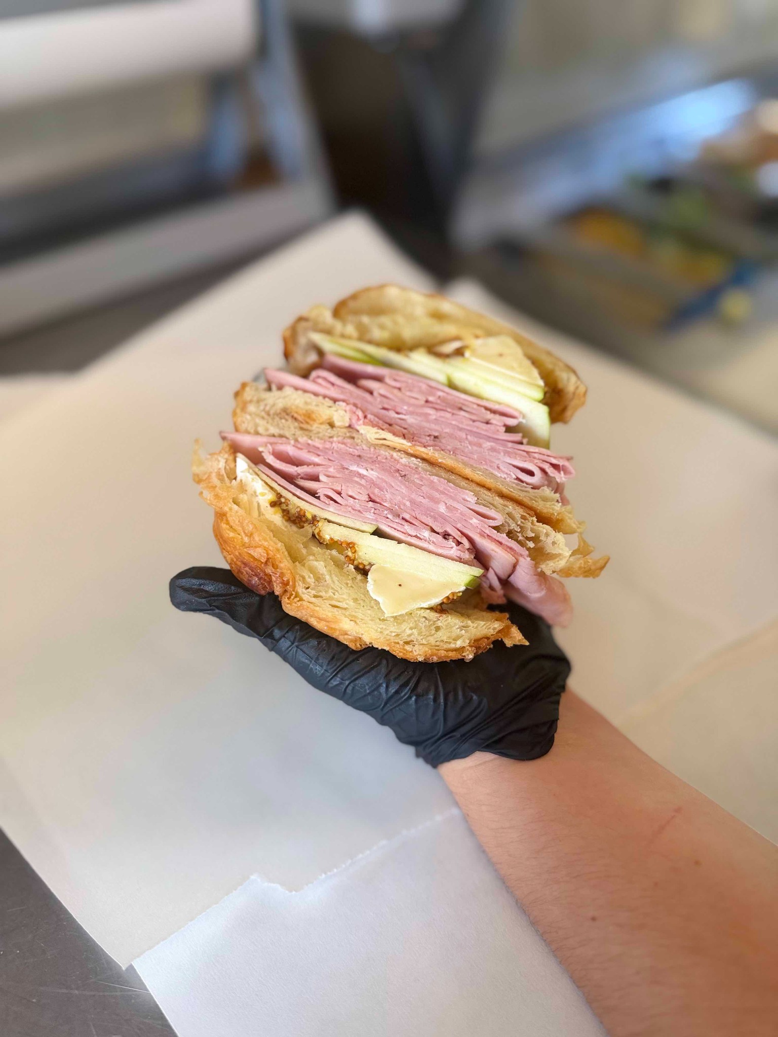 A ham, apple and cheese croissant sandwich being prepared